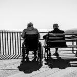 two elderly people sit on a bench