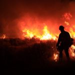 firefighter silhouetted against flames at night