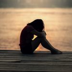 girl sitting on a dock with her head in her hands