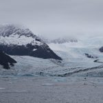 white glacier with ocean in foreground