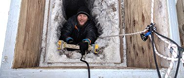 Oceanography graduate student Zac Cooper climbs down an icy ladder into the tunnel in May 2018. Researchers are harnessed to a rope for safety.