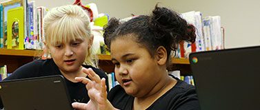 Two children using a computer laptop