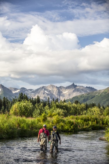 Two Alaska Salmon Program researchers cross a stream.