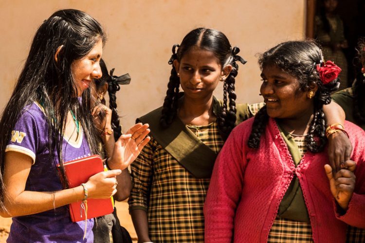 Cristina Lopez standing outside with a group of Indian schoolgirls in uniform