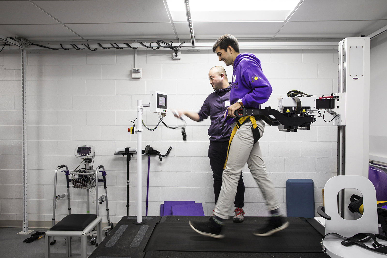 In the Amplifying Movement and Performance (AMP) Lab, Ph.D. student Soshi Samejima works with another student on a KineAssist treadmill for spinal-simulation research. A partnership between the UW’s Department of Rehabilitation Medicine and the College of Engineering, the lab advances understanding of both human and robot movement. (Photo by Mark Stone)