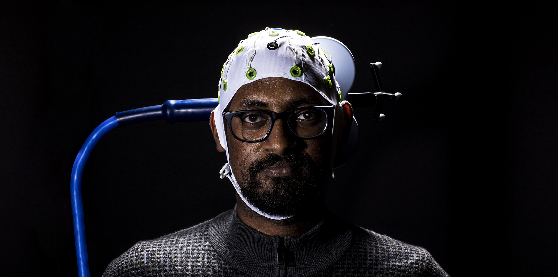 Psychology graduate student Theodros Haile demonstrates BrainNet, a Tetris-like game developed at the UW that uses a brain-to-brain interface. Haile’s cap processes brain signals from two other people, allowing them to play collaboratively using only their minds. (Photo by Mark Stone)
