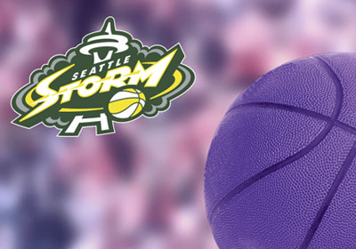 Seattle Storm logo over blurry purple spectators and purple basket ball