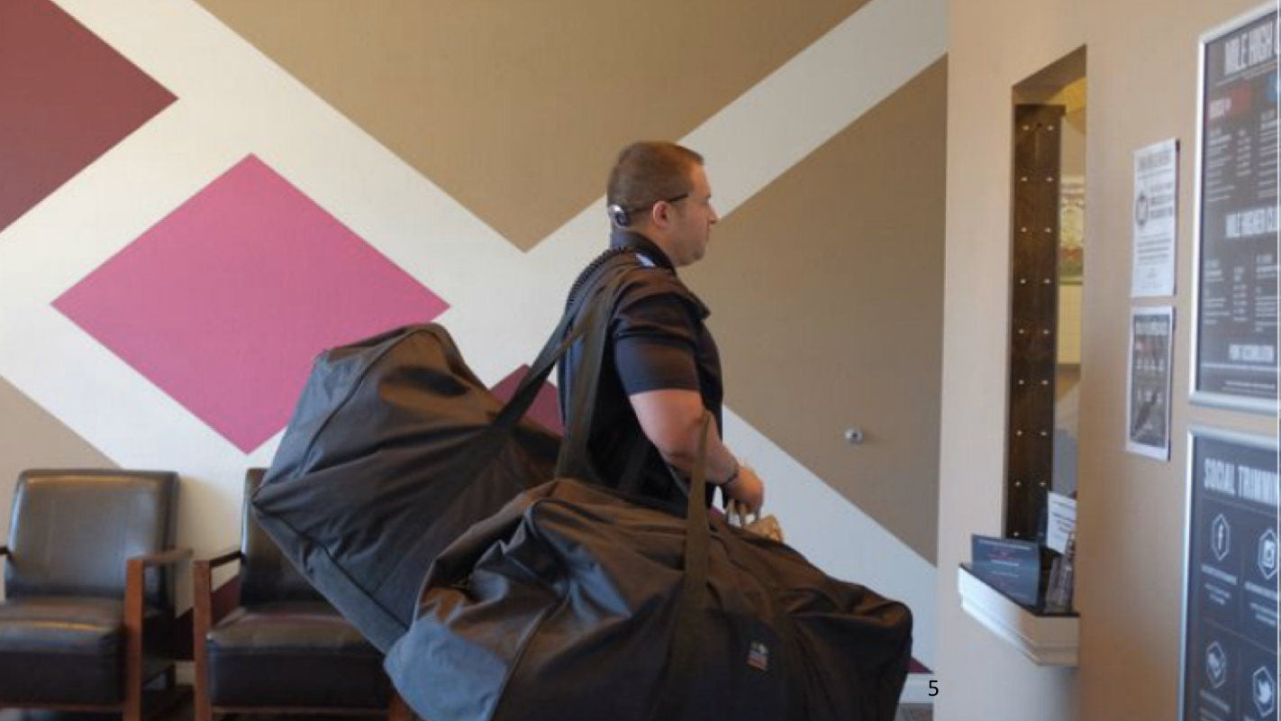 Picture of armed guard and duffle bags of cash