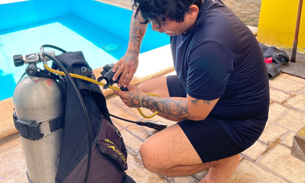 Buzo revisando su equipo antes de entrar al agua con lista de verificación en mano