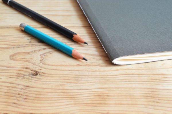 Notebook and pencils on a wood table
