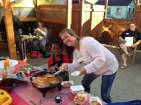 Talea Price poses with a young boy while serving food from the cooking demo table.